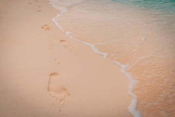 Tropical sandy beach with blurry blue ocean with footsteps.