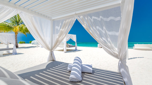 Amazing tropical beach scene with white canopy and curtain for luxury summer relaxation concept. Blue sky with white sand for sunny beach landscape background and summer vacation or holiday design