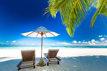 Exotic travel destination for couples and honeymooners, luxury resort beach with lounge chairs and umbrella. Tropical vacation, summer holiday concept