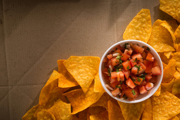 nachos chips and tomato salsa on a craft paper box