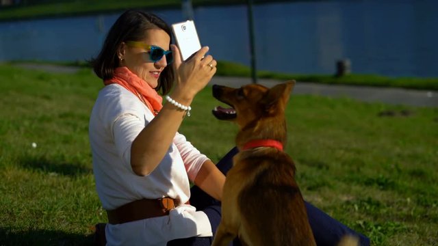Young, happy woman taking selfie with her dog in city park
