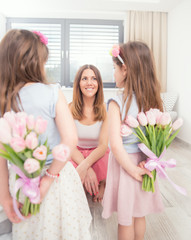 Happy mother's day concept. Cute little daughters with a tulip bouquet behind their back as a gift...