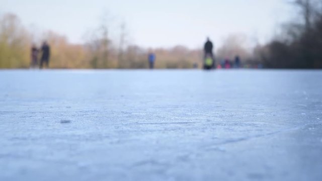 People ice skating on a frozen lake next to the river IJssel in Holland during a beautiful winter day winter. People are enjoying this typical Dutch winter activity.