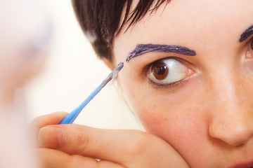 Girl paints her eyebrows closeup