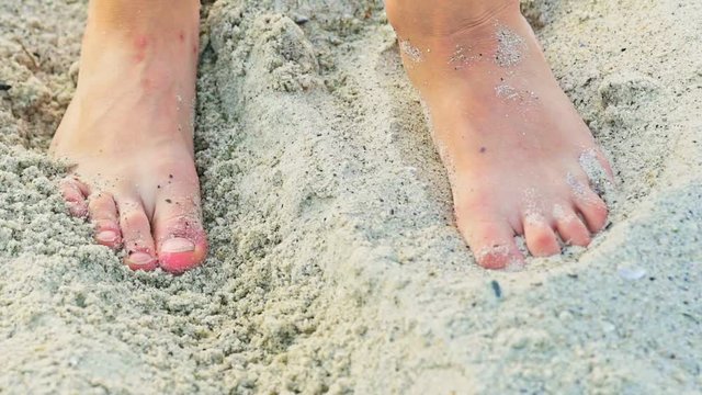 Feet of a human are rummaging sand on the beach in the summer in warm weather. Sandy shore. Rest on the sea.
