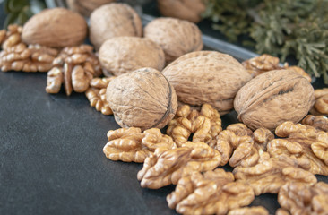 Walnut kernels near whole nuts on a black background.
