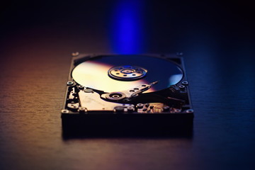 Open / disassembled hard drive on the table in dark colors and lighting close-up.