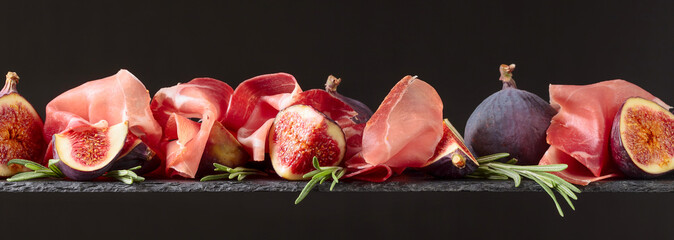 Prosciutto with figs and rosemary on a dark background.
