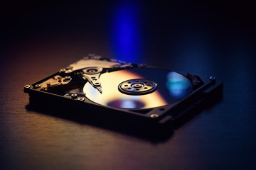 Open / disassembled hard drive on the table in dark colors and lighting close-up.