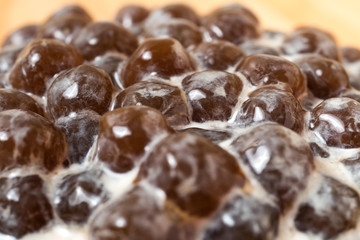 A glass cup of pearl milk tea (also called bubble tea) and a plate of tapioca ball on wooden background. Pearl milk tea is the most representative drink in Taiwan. Taiwan food . With copy space.