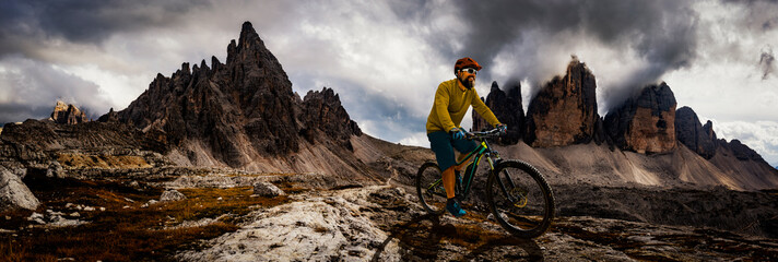 Single mountain bike rider on electric bike, e-mountainbike rides up mountain trail. Man riding on...