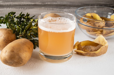 Potato juice in a glass near the whole potato and skarlupa.