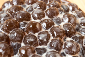 A glass cup of pearl milk tea (also called bubble tea) and a plate of tapioca ball on wooden background. Pearl milk tea is the most representative drink in Taiwan. Taiwan food . With copy space.