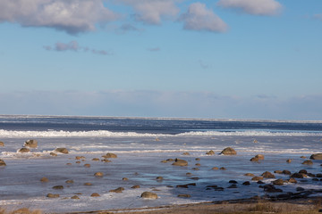 Seaside with frozen and melting ice with rocks