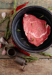 Raw beef steak with garlic, pepper and rosemary.
