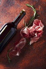 Prosciutto with rosemary and bottle of red wine.