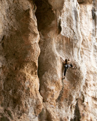 Girl rock climber climbs difficult route on the cliffs