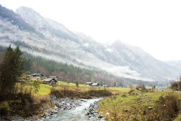 秋の雨の朝の雲が垂れ込めたリューチネ谷（スイス・ベルン州）