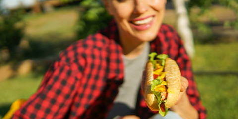 Young caucasian woman eating classic hot dog outdoors