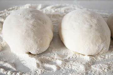 Fototapeta na wymiar Pieces of dough on a white table with flour.