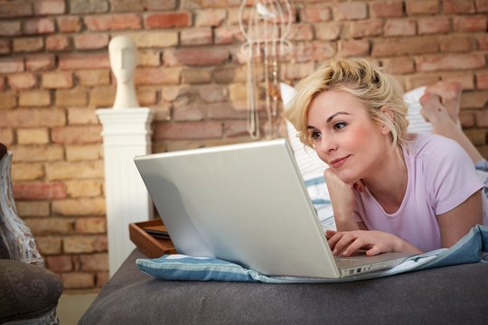 Smiling woman using laptop in bed