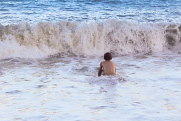 The boy frolics in the big waves