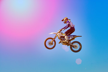 Fototapeta na wymiar Extreme sports background - silhouette of biker jumping on motorbike on sunset, against the blue sky