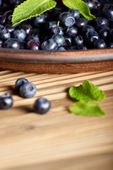 Clay plate full of Ripe organic blueberries on wooden table