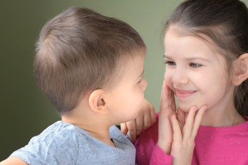 White caucasian toddler boy and girl look at each other with love on blurred neutral background. Cute little brother and beautiful sister with happiness faces looking at each other and smiling 
