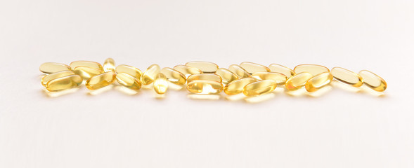 sunlit Fish oil capsules with omega 3 and vitamin D on a white background, isolated, healthy nutrition concept, close up shot.