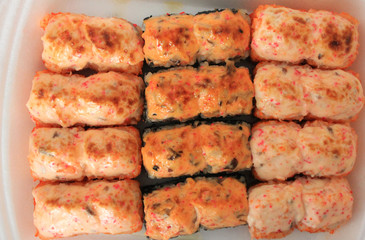 Sushi rolls top view in to go box. Baked salmon and eel unagi rolls on plate, tasty japanese food for lunch or dinner. Asian cuisine menu seafood options, tasty freshly cooked hot sushi close up view