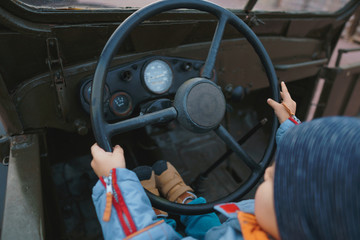 boy holding wheel in retro car