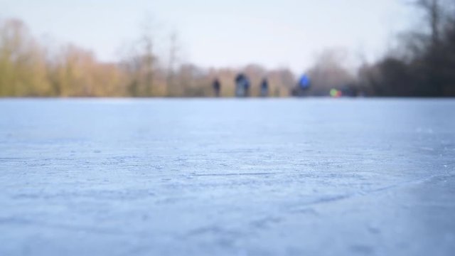 People ice skating on a frozen lake next to the river IJssel in Holland during a beautiful winter day winter. People are enjoying this typical Dutch winter activity.
