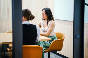 Two great ladies discussing a story inside a room. They look extraordinarily fit in their office type of clothing.