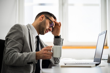 Fototapeta premium Young businessman is working in office. He is exhausted.