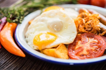 Typial breakfast with eggs, tomato, onion rings and sausage on plate