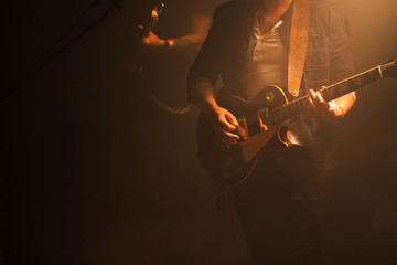 Guitarist on a dark stage - obrazy, fototapety, plakaty