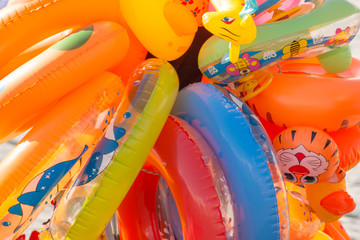 Close up of a large group of infatable floats and pool toys from a seller on the beach, on a warm summer day. Colorful pattern and animal themed, ideal for kids