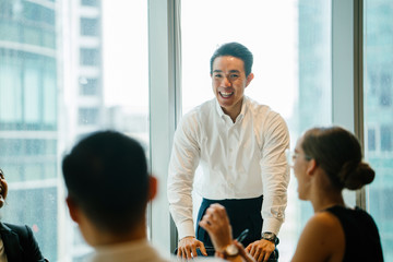 A young Asian Chinese professional is giving a presentation in front of his colleagues in the...