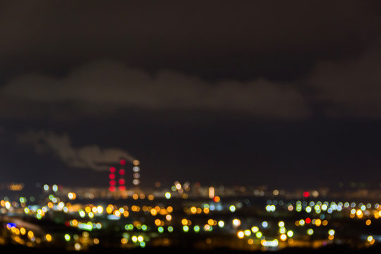 City skyline at night.Night view of a neighbourhood with low-rise apartment blocks illuminated window lights.Pipes of thermal power plant smoke.Blurry abstract image of industrial zone