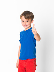 six year old boy in red trousers and blue shirt is posing in front of white background