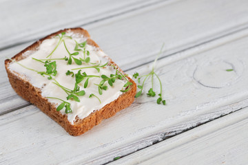 Cream Cheese on a slice of bread topped with fresh Cress . Wooden table