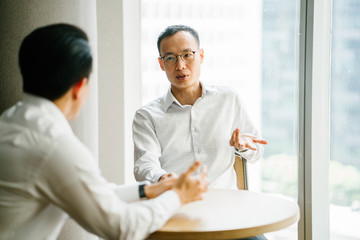 Image of two professional and competent entrepreneurs talking about a serious topic while sitting...