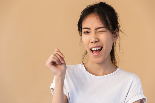 Photo of affable korean woman wearing basic t-shirt smiling and winking at you