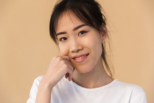 Photo of charming korean woman wearing basic t-shirt smiling and looking at camera
