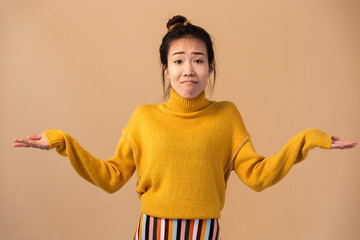 Image of innocent japanese woman wearing sweater throwing up hands with puzzlement