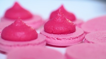 Pink pistachio macarons, squeezing and adding cream filling from pastry bag. Macaroons - delicious and beautiful french dessert. Cooking, food and baking, pastry concept.