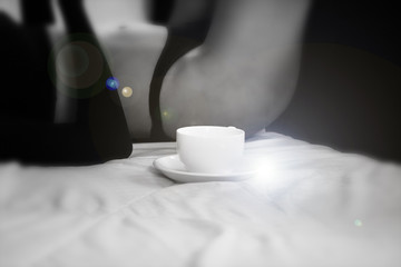 In selective focus of white ceramic coffee cup put on bed,blurry light around,len flare effect,black and white tone