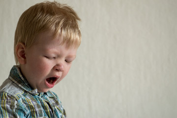 Fototapeta premium Caucasian blond boy misses and yawns. Space for copying