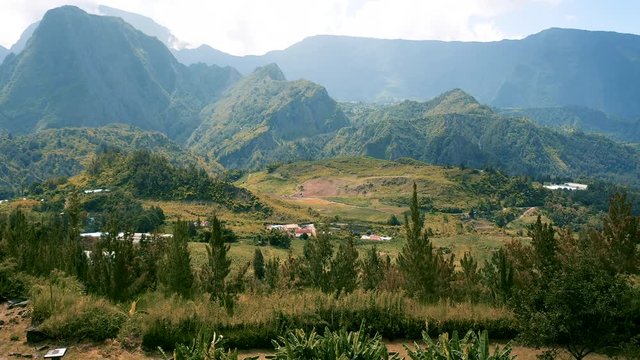 Drone rises high over the dramatic mountain landscape surrounding the town of Hell-Bourg on Reunion Island
